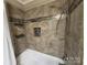 Tiled shower and tub featuring designer tile, a shower head, and built in shelves at 148 Palaside Ne Dr, Concord, NC 28025