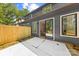 View of the backyard with gray siding, a wood fence, and a concrete patio with sliding glass doors at 2008 St John St, Charlotte, NC 28216