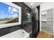 Modern bathroom featuring a soaking tub, black tiled shower, and a bright window with a neighborhood view at 2008 St John St, Charlotte, NC 28216