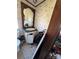 A dilapidated bathroom includes a damaged vanity, patterned wallpaper, and an adjacent toilet at 2504 Windswept Way, Rockwell, NC 28138