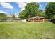 A spacious fenced backyard with a well-kept lawn, mature trees, and a storage shed, perfect for Gathering activities at 3203 Valleydale Rd, Monroe, NC 28110