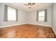 Large bedroom with hardwood floors, a modern ceiling fan, two windows with blinds, and light gray walls at 3203 Valleydale Rd, Monroe, NC 28110
