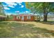 Charming brick home features a well-maintained lawn, fenced yard, and a small wooden deck perfect for enjoying the outdoors at 3203 Valleydale Rd, Monroe, NC 28110