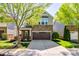 Charming two-story home boasts a stone facade, a two-car garage, and a neatly landscaped front yard with mature trees at 6024 Glenmore Garden Dr, Charlotte, NC 28270