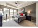 Comfortable main bedroom with a tray ceiling, ceiling fan, plush carpet, and bright natural light at 6024 Glenmore Garden Dr, Charlotte, NC 28270