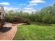Scenic backyard with brick patio, outdoor fireplace, and views of a pond surrounded by lush greenery at 6204 River Birch Dr, Gastonia, NC 28056