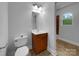 Cozy bathroom featuring a single sink vanity, toilet, tile floors, and a window at 6204 River Birch Dr, Gastonia, NC 28056