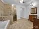 Bathroom featuring tile floors, walk-in shower, soaking tub, and a vanity with decorative mirror at 6204 River Birch Dr, Gastonia, NC 28056