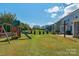 Backyard featuring a swing set, mature trees, and well-manicured lawn, ideal for and outdoor fun at 8008 Hudson Mill Dr, Waxhaw, NC 28173