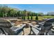 Brick fire pit area with stone seating, lush landscaping, and a black metal fence at 8008 Hudson Mill Dr, Waxhaw, NC 28173