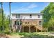 Back of house showing an elevated wooden deck and brick facade and lush yard at 8937 Penstemons Dr, Charlotte, NC 28215