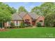 Charming brick home featuring manicured lawn, mature trees, and inviting curb appeal at 11424 Stonebriar Dr, Charlotte, NC 28277