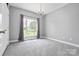 Bright bedroom with plush gray carpet, large window, and elegant chandelier, offering a serene and comfortable space at 121 Capstone Ct, Statesville, NC 28625