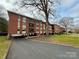 The exterior view highlights a brick condo building with covered parking and mature trees on a well-maintained lawn at 1300 Queens Rd # 210, Charlotte, NC 28207