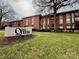 Brick condo building with '1300 Queens' sign, lawn, and mature trees creating a welcoming exterior view at 1300 Queens Rd # 210, Charlotte, NC 28207