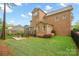 Brick home's backyard featuring a stone patio, screened in porch, wooden deck, flower beds and manicured lawn at 13044 Fen Ct, Huntersville, NC 28078