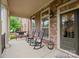 Inviting front porch featuring rocking chairs, bench, and views of the landscaped yard at 13044 Fen Ct, Huntersville, NC 28078