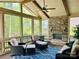 Relaxing sunroom features a stone fireplace, comfortable seating, and a view of the landscaped backyard at 13044 Fen Ct, Huntersville, NC 28078
