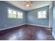 Empty bedroom with hardwood floors, two windows, blue walls, and a ceiling fan at 1407 Clarksville Campground Rd, Monroe, NC 28112