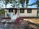 Charming home with a white brick facade, black shutters, and a welcoming front porch and a cute white dog at 1407 Clarksville Campground Rd, Monroe, NC 28112