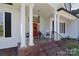 Welcoming front porch with white columns, a red door with a wreath, and rocking chairs at 16610 Blackberry Hills Dr, Midland, NC 28107