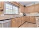 Well-lit kitchen with stainless steel appliances, granite countertops, natural wood cabinets, and a sink with a window at 16610 Blackberry Hills Dr, Midland, NC 28107