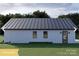 Back of a contemporary farmhouse with white siding, metal roof, and neat landscaping with green lawn at 180 Nc 742 Hwy, Wadesboro, NC 28170