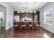 A kitchen island features dark cabinetry, granite countertops, pendant lighting and bar stool seating at 2220 Atwell Glen Ln, Pineville, NC 28134