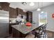 A kitchen island with seating shows granite countertops, dark cabinets and a mosaic backsplash at 2220 Atwell Glen Ln, Pineville, NC 28134