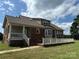 Rear exterior elevation of a tan and brick house, featuring a white porch and lush green lawn at 2417 Lynwood Dr, Lancaster, SC 29720