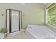 Bright bathroom featuring a glass enclosed shower, soaking tub near the window, and neutral tile floors at 2805 Bathgate Ln, Matthews, NC 28105