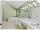 Bright bathroom featuring a large soaking tub, double vanity with marble countertop, and neutral tile floors at 2805 Bathgate Ln, Matthews, NC 28105