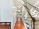 Inviting hallway featuring hardwood floors, stairs with black handrail and a glimpse of the bright kitchen ahead at 2805 Bathgate Ln, Matthews, NC 28105