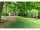 Backyard featuring a tree swing and storage shed in a wooded area at 4813 Carving Tree Dr, Mint Hill, NC 28227