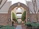 Charming brick archway offering a serene view of a landscaped courtyard with a central fountain in the condo community at 5007 Sharon Rd # R, Charlotte, NC 28210
