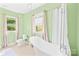 Bathroom includes a soaking tub, toilet, window, and shower with a curtain and green walls at 621 N 9Th St, Albemarle, NC 28001