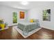 Bright bedroom with hardwood floors, two windows, and a colorful bedspread at 6724 Brushwood Dr, Charlotte, NC 28262