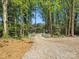 Long gravel driveway lined with trees and white fencing leading to a charming home at 6724 Brushwood Dr, Charlotte, NC 28262