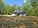 Renovated home surrounded by mature trees, featuring a covered porch and manicured grounds at 6724 Brushwood Dr, Charlotte, NC 28262