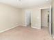 Neutral bedroom featuring carpeted floors, light walls, and two access doors at 7638 Carrington Forest Ln, Matthews, NC 28105