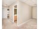 Hallway featuring tan walls and carpet, with view into bathroom at 7638 Carrington Forest Ln, Matthews, NC 28105