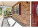 Covered porch features stone accent wall, window with shutters, and a red front door at 7638 Carrington Forest Ln, Matthews, NC 28105