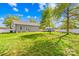 Wide shot of backyard featuring green grass, a small storage shed, privacy fence, and clear blue skies at 911 Earl St, Shelby, NC 28150