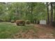 Spacious backyard with mature trees, lush lawn, and a storage shed in a wooded setting at 9208 Plashet Ln, Mint Hill, NC 28227