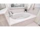 Bright bathroom showcasing a tile surround jacuzzi tub and a sunny window at 9208 Plashet Ln, Mint Hill, NC 28227