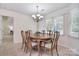 Bright dining room features chandelier, wood table and chairs, with windows providing natural light at 9208 Plashet Ln, Mint Hill, NC 28227