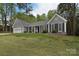 Inviting single-story home with gray siding, black shutters, and mature trees in a serene setting at 9208 Plashet Ln, Mint Hill, NC 28227