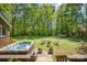 Backyard with hot tub, putting green, firepit, and hammock surrounded by lush trees at 127 Fantasy Ln, Mooresville, NC 28117