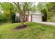 Charming brick home with red front door and shutters, landscaped yard, and two-car garage at 13228 Crooked Pine Ct, Charlotte, NC 28215