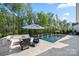 Modern outdoor pool with lounge area and seating, surrounded by mature trees and privacy fencing at 14013 Pinoli Pine Cir, Huntersville, NC 28078